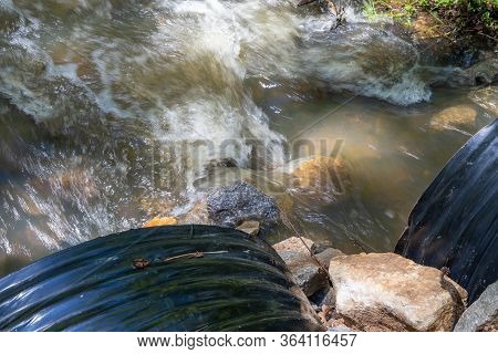 Overhead View Of Water Flowing Rapidly Out Of Two Large Black Drain Pipes, Environmental Pollution A