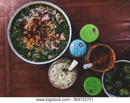 Top view on a traditional pho bo on a dark table. Pho bo is Vietnamese fresh rice noodle soup with beef, herbs and chili. Vietnam's national dish