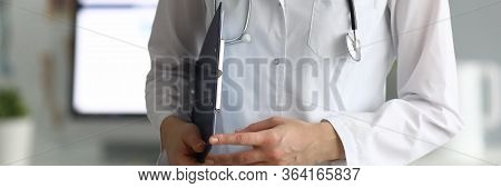 Close-up Of Experienced Doctor Working In Hospital. Practitioner Holding Paper Folder With Informati