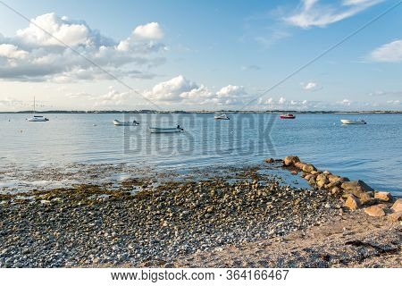 Scenic Stony Beach And Rocks With Boats In The Background At The Baltic Sea In Northern Germany