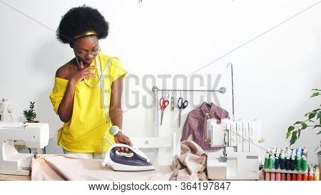 African-american Seamstress Smoothes The Fabric With An Iron At Her Workplace, The Seamstresss Workp
