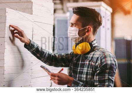 Portrait Male Foreman Inspector In Medical Face Mask And Protective Headphones Checking Woodwork Sto