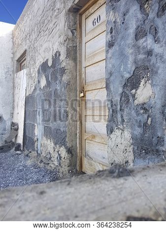 Abandoned Stone House With Lock On Wooden Closed Door. No People Living Here. Sunny Day With Blue Sk