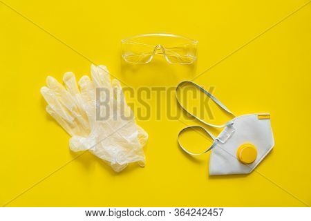Respirator Ffp, Rubber Gloves And Protective Glasses Lie On A Yellow Background. Anti-virus Protecti
