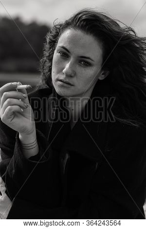 Serious Curly Woman With A Cigarette In Her Hands