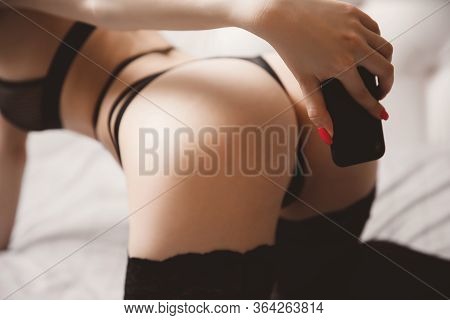 Beautiful Woman Photographs Herself In Lingerie On Phone For Guy. Virtual Sex Model Concept