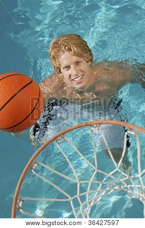 Jeune homme jouant au basketball de l'eau dans la piscine