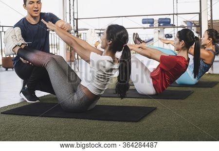 Three Long-haired Latin Women Led By The Instructor Doing Sit-ups In The Gym Lifestyle Concept