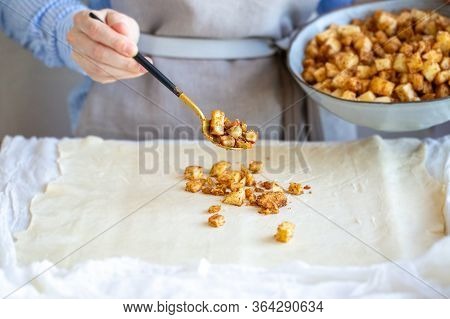 Cooking Apple Strudel. Girl Is Preparing A Pie At Home In An Apron. Work With Puff Pastry. The Proce