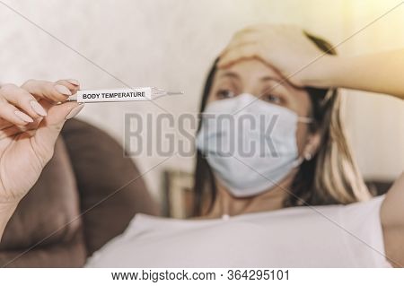 Girl Looks Sadly At The Thermometer Showing A High Temperature , Get Sick With The Flu Virus During 