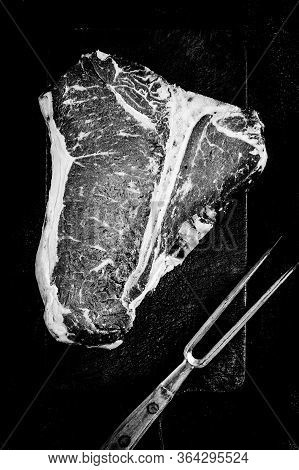 Dry Aged Premium Raw T-bone Steak On Chopping Board. Black And White Usda Prime Beef.