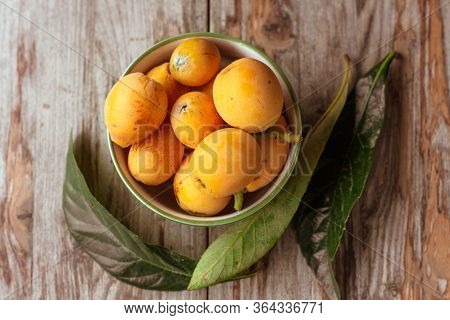 Ripe Medlar Fruit , Eriobotrya Japonica, And Green Medlar Leaves On Wooden Table. Top View