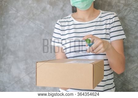 Asian Woman Wears Mask Using Spray Alcohol Sanitizer Cleaning Parcel Post, To Prevent The Virus And