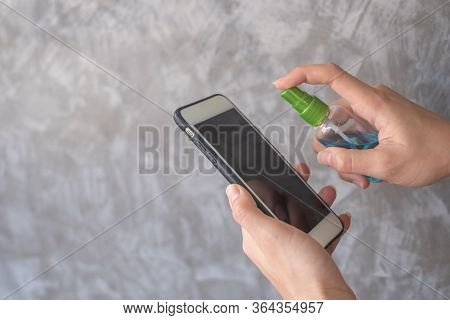 Closeup Woman Hands Using Spray Alcohol Sanitizer Cleaning Screen Smartphone, To Prevent The Virus A