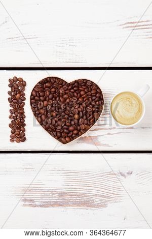 I Love Fresh Cappuccino With Foam. Roasted Coffee Seeds Arranged In A Shape Of Heart. White Wood Bac