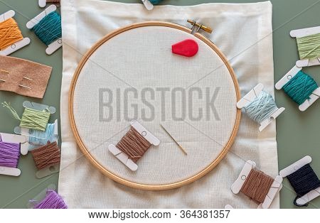 Embroidery Tools On Green Background With Wooden Embroidery Hoop, Needles, Needle Threader And Color