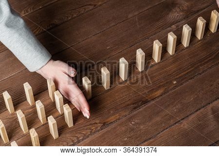 Businesswoman Protecting Dominoes From Falling On Wooden Desk. Business Assistance And Leadership In