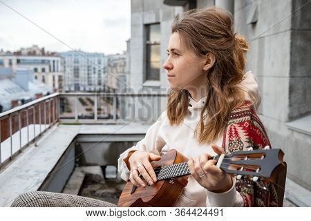 Young Caucasian Hipster/hippie Woman In Casual Clothes Playing On Hawaiian Guitar, Sings A Song On A