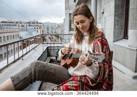 Young Caucasian Hipster/hippie Woman In Casual Clothes Playing On Hawaiian Guitar, Sings A Song On A