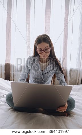 Remote Work At Home, Female On The Bed During The Day Working With A Laptop, Looking On The Screen.