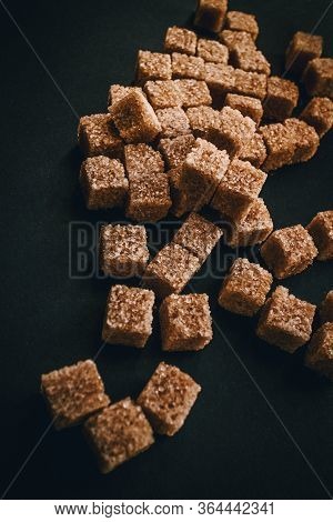 Brown Cane Sugar In Cubes On A Black Background. Still Life. Carbohydrates And Non-diet Food. Calori