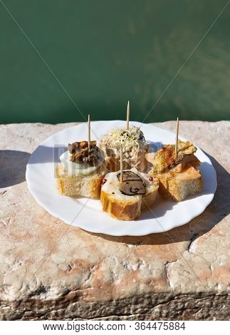 Traditional Venetian Appetizers Cicchetti On Turquoise Green Water Of Canal Background. Venice, Ital