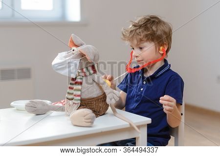 A Cute Little Boy Plays A Doctor And Listens With A Statoscope To The Lungs Of A Rat Toy Infected Wi