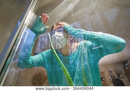 Woman With Medical Mask On Their Faces Looking Through Window, Stay At Home, Selfisolation To Preven