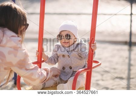 Adorable Little Girl On The Swing Set In Playground. Happy Little Girl Have Fun. One And Hulf Year G