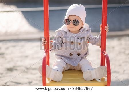 Adorable Little Girl On The Swing Set In Playground. Happy Little Girl Have Fun. One And Hulf Year G