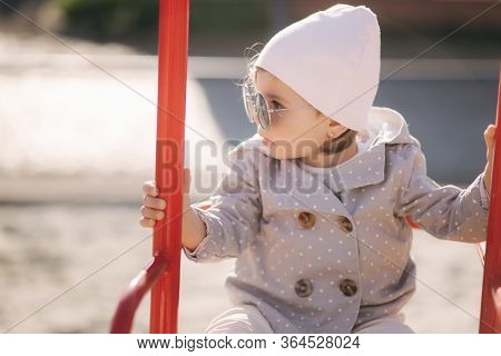 Adorable Little Girl On The Swing Set In Playground. Happy Little Girl Have Fun. One And Hulf Year G