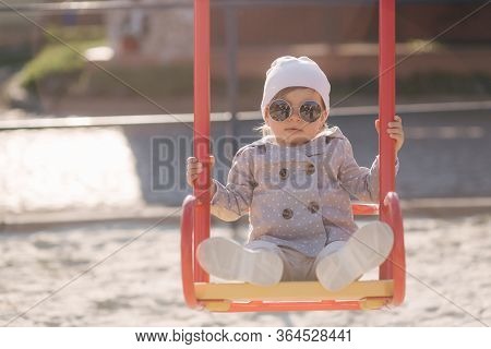 Adorable Little Girl On The Swing Set In Playground. Happy Little Girl Have Fun. One And Hulf Year G