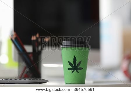 On Table Is A Paper Cup With Lid Painted Hemp. Legalized Stand-alone Drink With Hemp. Flavored Organ