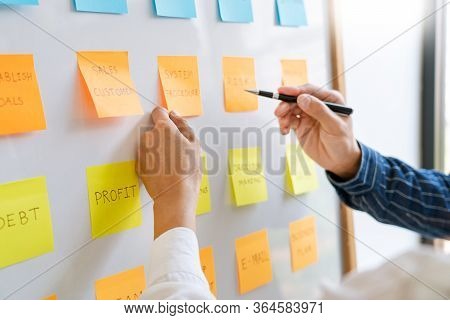 Young Business Workers Posting With Sticky Notes Stickers Reminders  Creative Brainstorming At Board