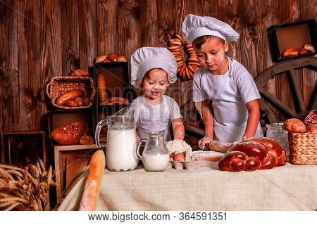 Cheerful Kids Playing Chefs And Hats Play The Role Of Baker.
The Table Is Full Of Clutter. The Mood 
