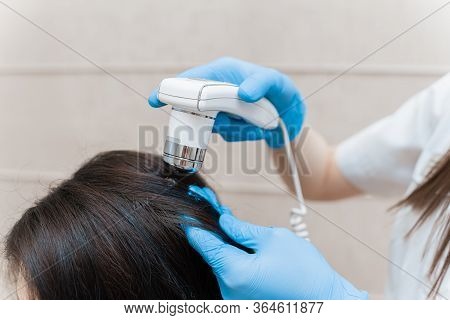 Trichoscopy Of Hair And Scalp Closeup. Trichoscope In The Hands Of A Doctor