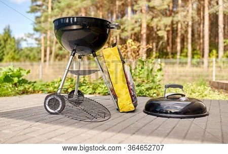 bbq and grilling concept - grill brazier and bag of charcoal outdoors