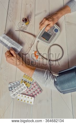 Senior Wrinkled Hands With Blood Pressure Measure Cuff, Medicine Bottle, Glass, Colorful Pills, Ther