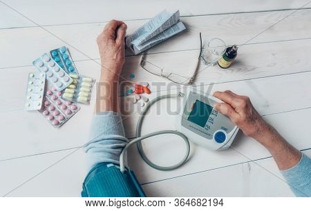 Senior Wrinkled Hands With Blood Pressure Measure Cuff, Medicine Bottle, Glass, Colorful Pills, Ther