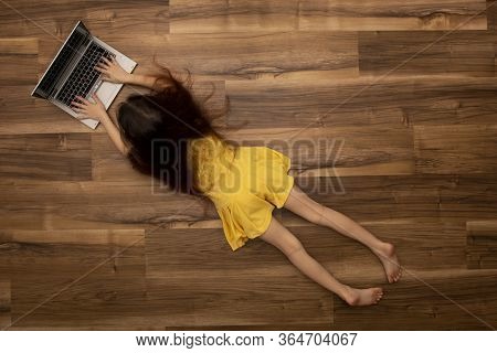 Top View Of A Girl Working With A Laptop And Shows A Blank Screen Lying On The Floor At Home.