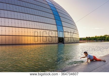 Beijing / China - July 12, 2016: Boy Playing In Front Of The National Centre Of Performing Arts Ncpa
