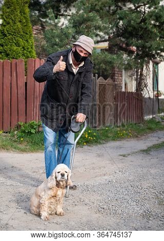 Senior Man In Protective Mask With A Cane Walking With A Dog In Sunny Day