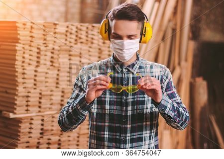 Portrait Male Carpenter In Protective Headphones On Ears, Medical Mask On Face Wearing Protective Gl