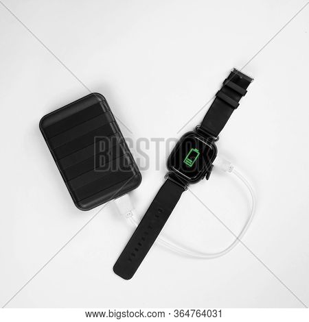 Smart Watch And Powerbank On A White Background. Powerbank Charges The Watch.flat Lay
