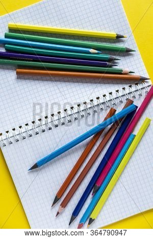 School Supplies On Yellow. Bright Back To School Background. Notepad And Stack Of Colorful Pencils. 