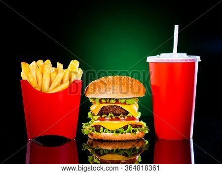 Tasty hamburger and french fries on a dark green background