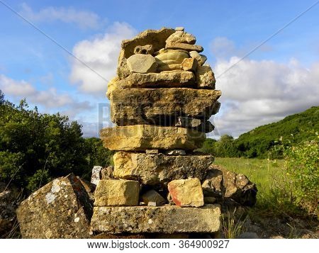 Balanced Stones On A Background Of Blue Sky And Green Trees. Stone Tower, Balanced Rock Sculpture.