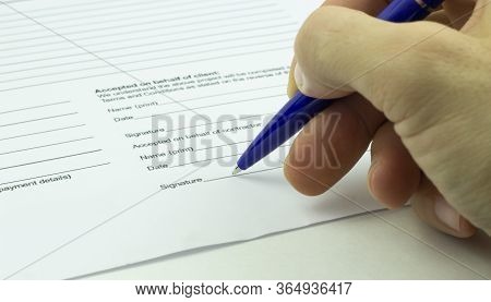 A Man Signs A Contract With A Blue Ballpoint Pen.