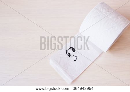 Toilet Paper With Funny Smiling Face On Wooden Background, Copyspace. Supplies For Quarantine Isolat