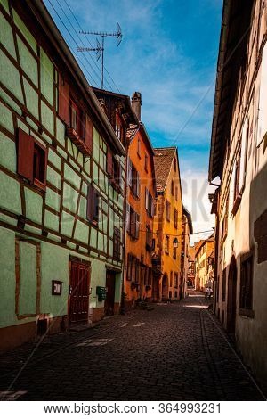 colorful halftimbered houses along a narrow street with cobblestones in the medieval town of Riquewihr, Alsace Region, France
